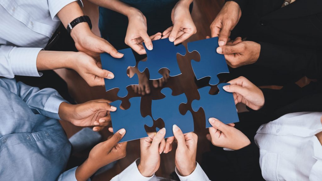 Mehrere Menschen fügen Puzzle-Teile zusammen